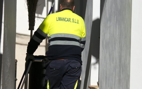 a-man-in-a-yellow-and-black-uniform-is-cleaning-the-street.jpg A man in a yellow and black uniform is cleaning the street