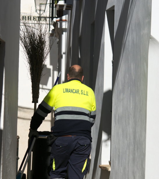 a-man-in-a-yellow-and-black-uniform-is-cleaning-the-street.jpg A man in a yellow and black uniform is cleaning the street