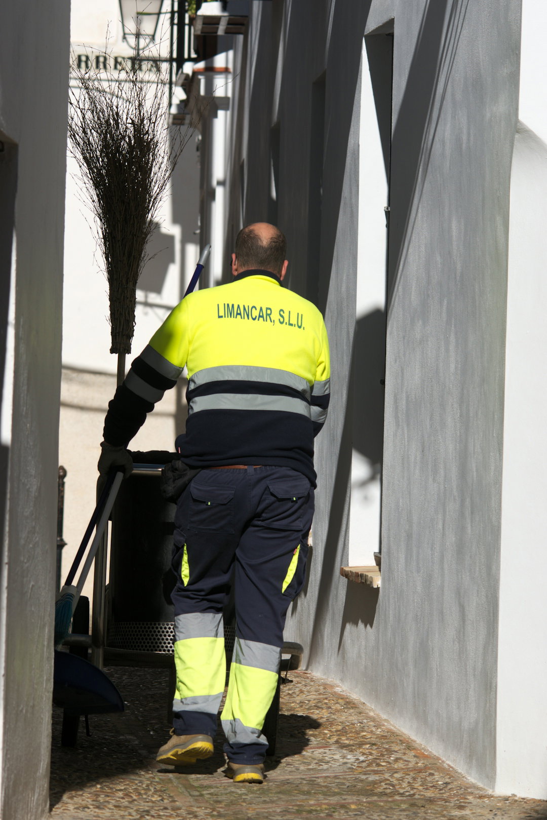 A man in a yellow and black uniform is cleaning the street